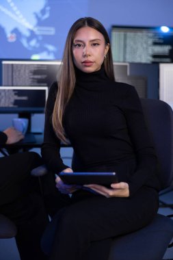 Güvenlik Operasyon Merkezi SOC 'da Siber Güvenlik Analisti olarak çalışan kendine güvenen bir kadının portresi. Arka planda harita ve SIEM sistemi.
