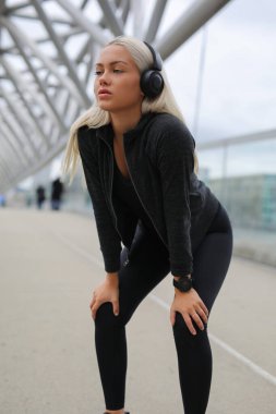 Kulaklıklı kararlı bir kadın şehir dışındaki bir yerde antrenmanını durduruyor..