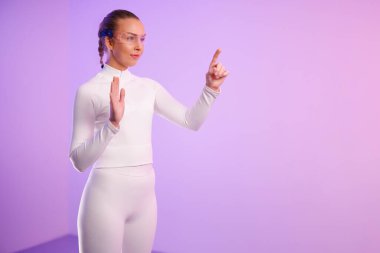 Mor arkaplanı işaret eden akıllı gözlüklü genç bir kadın.