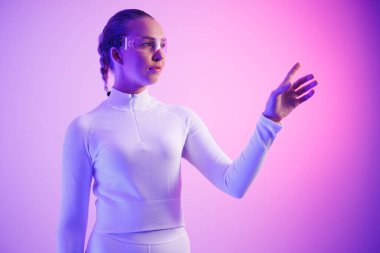 Akıllı gözlüklü bir kadın aydınlanmış neon ışığa karşı jest yapıyor.