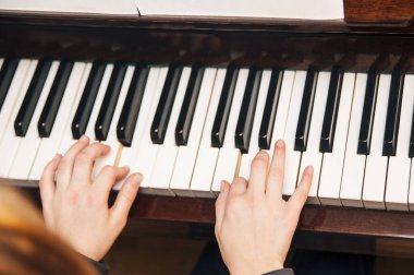 Bir müzik okulunda genç bir kız piyano çalar. Piyano anahtarının üst görüntüsü. Kız yeni müzik besteleri çalmayı öğreniyor.