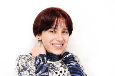 Beyaz arka planda mutlu bir genç kızın portresi, gülümseyen bir kız, sağlıklı beyaz dişleri ve kısa kızıl saçları var. Kız ergenlik depresyonuna son verdi ve ailesiyle barıştı. İzole edilmiş