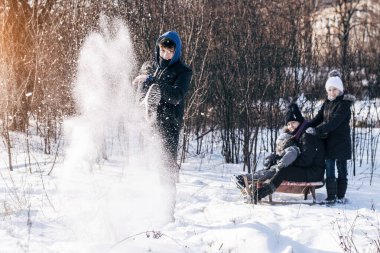 Aileler güzel, güneşli, karlı bir günde kızakla kayarken aileleriyle vakit geçiriyorlar. Yatay