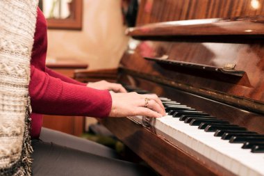 İşten sonra, evde dinlenen kadın en sevdiği melodilerle piyano çalar. Yatay olarak. Piyano çalmak, zor ve stresli bir iş gününden sonra bir kadının sakinleşmesine yardımcı olur.