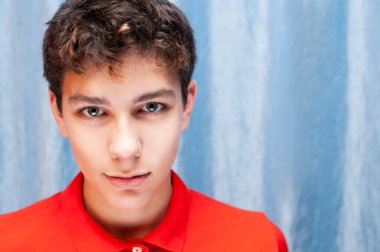 Mavi arka planda, kırmızı tişörtlü genç bir çocuk, büyüleyici bir gülümsemesi var. Adam sağlıklı olduğu ve baş ağrısı olmadığı için mutlu.