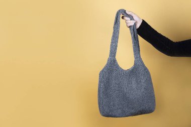 Kadın elinde turuncu arka planda rahat bir kumaş torba tutuyor, son zamanlarda kadın ekolojik olmayan selofan torbaları kullanmıyor. Ekolojik poşetlerle alışveriş kavramı