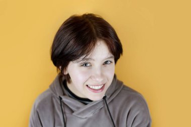 Ergenliğin başlangıcında tatlı bir genç kız, kız gülümsüyor ve çok mutlu, iyi gidiyor, güzel bir gülümsemesi, beyaz dişleri var. Kız, ailesinden sevgi ve koruma hissediyor.