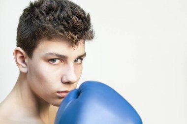 Ellerinde boks eldivenleri olan kızgın, üzgün yüzlü genç bir çocuğun portresi. Bir çocuk okulda aşağılanmaktan hoşlanmaz, zorbalığa karşıdır. Boşluğu kopyala