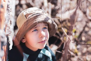 Ormandaki küçük bir çocuğun dramatik portresi. Gökyüzüne bakıp yardım bekleyen büyük mavi gözleri var. Parktaki yakışıklı ama üzgün çocuk, belki de kaybolmuştur.