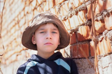 7-8 yaşlarında üzgün bakışlı küçük bir çocuk evin gölgesinde duruyor, büyük çocuklar tarafından aşağılanıyor ve şimdi ahlâki açıdan iyi değil, zorbalığa ve şiddete karşı kavram.