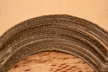 Oluklu karton yarım daire şeklinde uzanıyor. Yuvarlak karton çarşaflar, yuvarlak nesnelerin özel paketlenmesi için hazırlanır. Seçici odak