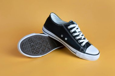 Turuncu arka planda beyaz bağcıklı ve güçlü tabanlı rahat spor kumaş ayakkabılar. Koşmak, bisiklete binmek, basketbol oynamak için spor ayakkabıları.