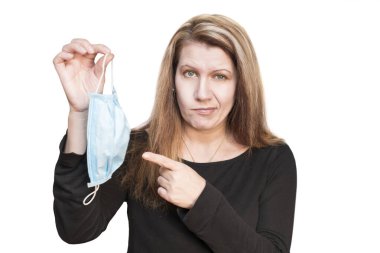 Beyaz arka plandaki bir kadın elinde tıbbi bir maske tutuyor ve üzerinde parmağını gösteriyor. Üşüttüğü ve evde tıbbi maske takması gerektiği için kadın memnun değil. 