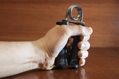 Elleri metali plastik saplı, elle genişletmeli tahta arka planda sıkıştırıyor. Güç kavramı, erkek cesareti.