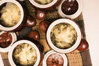 İçinde yiyecek olan kil çömlek. Mantarlı patates, sebze ve peynir. Lezzetli ve sağlıklı yiyecekler. Üst görünüm