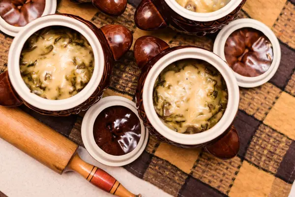 Evde kil kaplarda pişirilmiş peynirli ve mantarlı lezzetli ev yapımı etli börekler. Tencerelerin yanında mangırı elle sarmak için tahta aletler var. Yatay