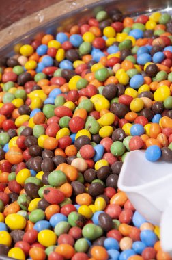 Parlak renkli yuvarlak şekerlerden oluşan büyük bir kalp, mavi bir arka planda cereyanlar. Şekerleme. Eğlenceli bir tatil. Çocukların tatlıları.