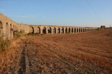 Nefes kesen bir günbatımı, Monte Romano 'daki antik Roma su kemeri kalıntılarının üzerine sıcak, altın rengi döküyor. Yıpranmış taş kemerler dimdik, renkli gökyüzüne karşı siluet, tarih ve ebedi güzelliği çağrıştırıyor..