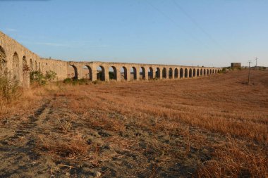 Nefes kesen bir günbatımı, Monte Romano 'daki antik Roma su kemeri kalıntılarının üzerine sıcak, altın rengi döküyor. Yıpranmış taş kemerler dimdik, renkli gökyüzüne karşı siluet, tarih ve ebedi güzelliği çağrıştırıyor..