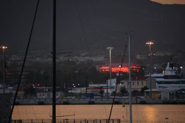 olbia , ITALY - aug 15 -2024 : An elegant yacht moored in the harbor at sunset: the sky fades into warm shades of orange clipart