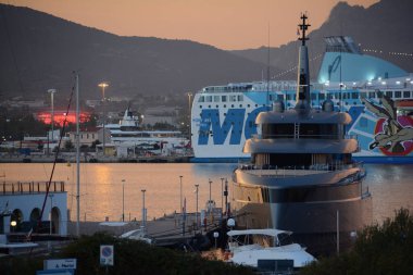 Olbia, ITALY - 15 Ağustos 2024: limanda gün batımında demirlemiş zarif bir yat: gökyüzü ılık turuncu gölgeler içinde kaybolur