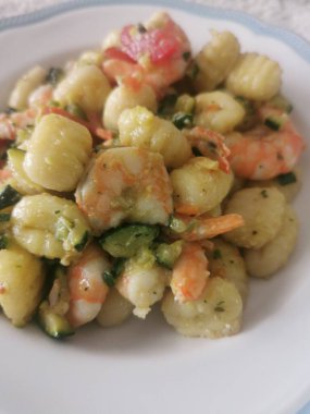 Yumuşak karides, doğranmış kabak ve vişneli domatesle servis edilen lezzetli bir tabak kremalı gnocchi. Bu canlı deniz ürünleri makarnası rahatlatıcı ama zarif bir yemek için mükemmel.. 