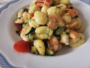 Yumuşak karides, doğranmış kabak ve vişneli domatesle servis edilen lezzetli bir tabak kremalı gnocchi. Bu canlı deniz ürünleri makarnası rahatlatıcı ama zarif bir yemek için mükemmel.. 