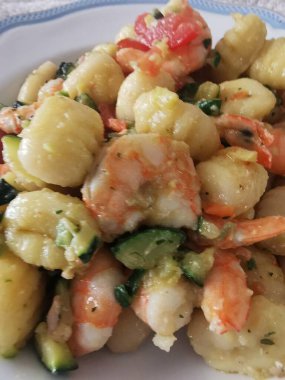 Yumuşak karides, doğranmış kabak ve vişneli domatesle servis edilen lezzetli bir tabak kremalı gnocchi. Bu canlı deniz ürünleri makarnası rahatlatıcı ama zarif bir yemek için mükemmel.. 