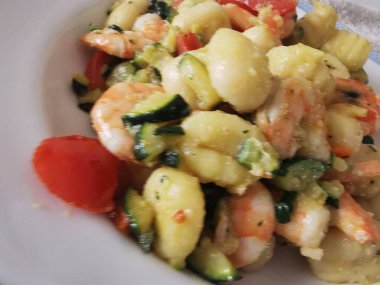 Yumuşak karides, doğranmış kabak ve vişneli domatesle servis edilen lezzetli bir tabak kremalı gnocchi. Bu canlı deniz ürünleri makarnası rahatlatıcı ama zarif bir yemek için mükemmel.. 
