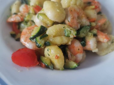 Yumuşak karides, doğranmış kabak ve vişneli domatesle servis edilen lezzetli bir tabak kremalı gnocchi. Bu canlı deniz ürünleri makarnası rahatlatıcı ama zarif bir yemek için mükemmel.. 