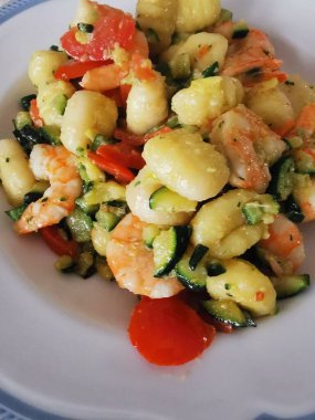 Yumuşak karides, doğranmış kabak ve vişneli domatesle servis edilen lezzetli bir tabak kremalı gnocchi. Bu canlı deniz ürünleri makarnası rahatlatıcı ama zarif bir yemek için mükemmel.. 