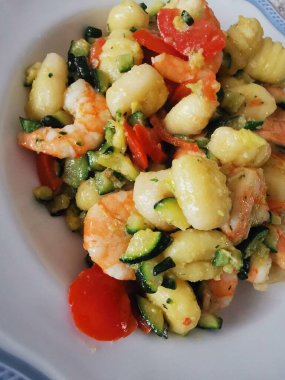 Yumuşak karides, doğranmış kabak ve vişneli domatesle servis edilen lezzetli bir tabak kremalı gnocchi. Bu canlı deniz ürünleri makarnası rahatlatıcı ama zarif bir yemek için mükemmel.. 