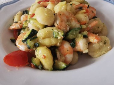 Yumuşak karides, doğranmış kabak ve vişneli domatesle servis edilen lezzetli bir tabak kremalı gnocchi. Bu canlı deniz ürünleri makarnası rahatlatıcı ama zarif bir yemek için mükemmel.. 