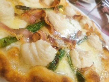 İçinde kremalı ricotta kıvrımları, çıtır domuz pastırması, taze kuşkonmaz ve kahverengi kabuklu erimiş peynir olan lezzetli bir zanaatkar pizza. Mükemmel pişmiş ve lezzetten patlıyor..