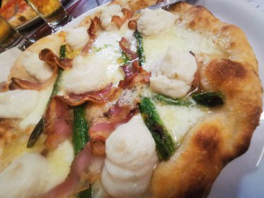 İçinde kremalı ricotta kıvrımları, çıtır domuz pastırması, taze kuşkonmaz ve kahverengi kabuklu erimiş peynir olan lezzetli bir zanaatkar pizza. Mükemmel pişmiş ve lezzetten patlıyor..
