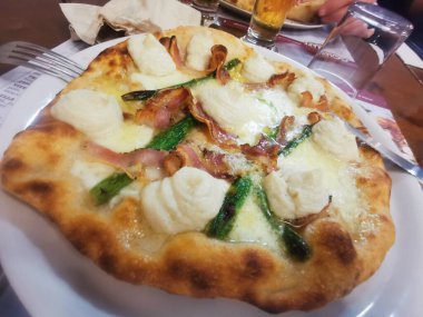 İçinde kremalı ricotta kıvrımları, çıtır domuz pastırması, taze kuşkonmaz ve kahverengi kabuklu erimiş peynir olan lezzetli bir zanaatkar pizza. Mükemmel pişmiş ve lezzetten patlıyor..