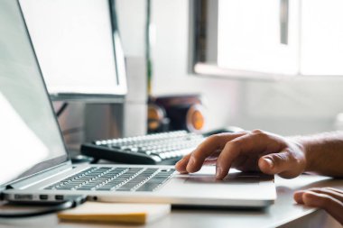 Person using the touchpad of a modern laptop. Unrecognizable young man working at his desk with computers. Freelance man working, student doing homework with computer, teleworker connecting online.