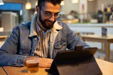 Fırının içindeki tablete bakan sakallı yakışıklı bir adam.