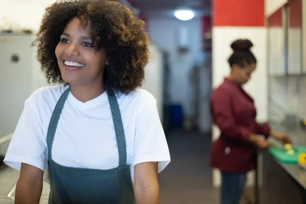 年轻的非洲女服务员带着在工作中做饭的背景微笑 — 图库照片