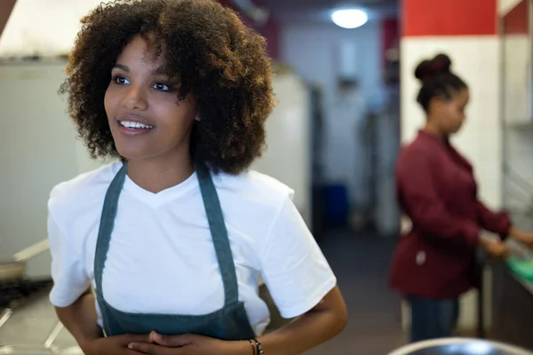 年轻的卷发非洲女服务员 带着厨师的背景在工作中交谈 — 图库照片