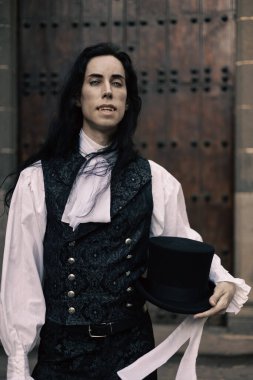 Kalesinin ahşap kapısının dibinde uzun siyah saçlı yakışıklı gotik vampir.