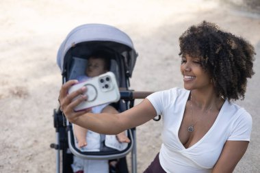 Anne bebek arabasında uyuyan bebeğiyle selfie çekiyor.