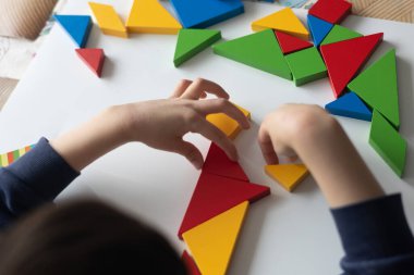 Renkli ahşap üçgenlerle oynayan çocuk eğitim yoluyla iyi motor becerileri ve yaratıcılığı geliştiriyor.