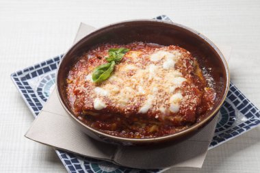 Bol soslu lazanya bolonez. Süslü bir yere yerleştirilmiş taze fesleğen yaprağıyla süslenmiş et sosu.