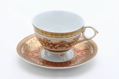 Barok desenli, altın ve kırmızı süslemelerle süslenmiş, rafine çay içme deneyimini sembolize eden narin porselen çay fincanı.