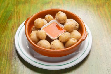 Wrinkled potatoes native to canary islands, accompanied by spicy mojo sauce in rustic ceramic serving dish clipart