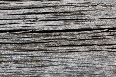 Yıpranmış gri ahşap yüzey derin, karmaşık çatlakları ortaya çıkarıyor. Yaşlanmış kerestenin yapısını gösteren organik, dokulu desenler oluşturuyor.