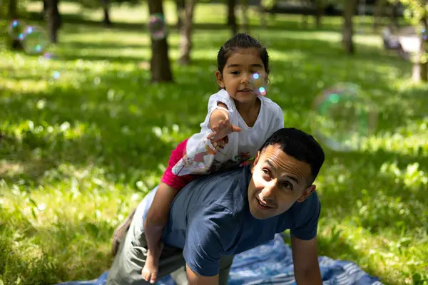 Babası köpük üflerken kızı onları yakalıyor, açık havada neşeli bir yaz günü geçiriyor.