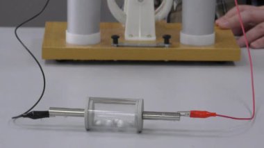 Bir dielektrik silindirde yüklü metalik küreler, yüklerine dayalı olarak elektrostatik prensipleri çizer ya da iter..