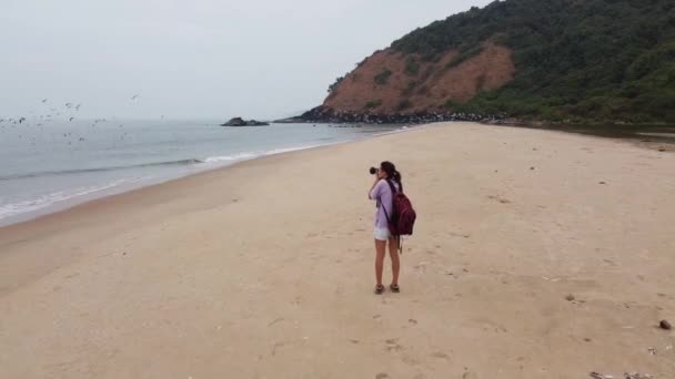 Uma Mulher Fotografa Mar Numa Praia Vazia Gaivotas Sobrevoam Mar — Vídeo de Stock